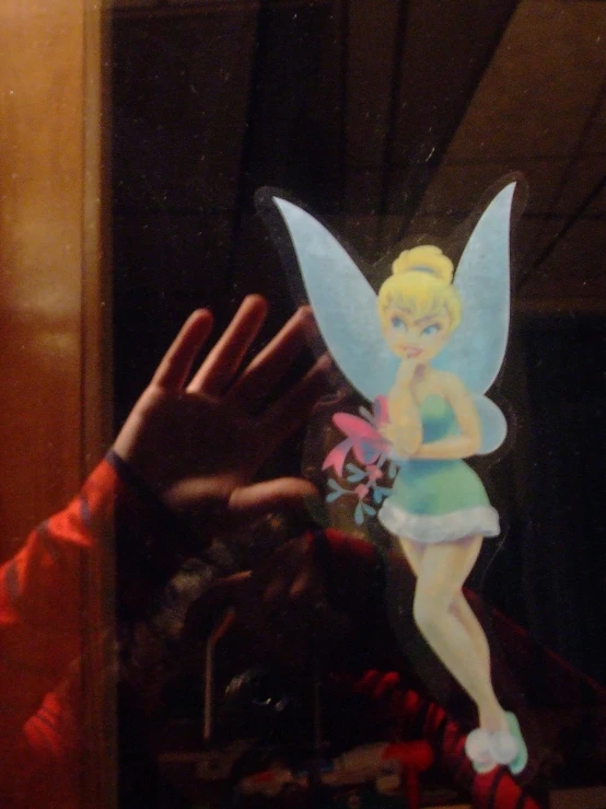 a hand is holding a tinker bell paper doll