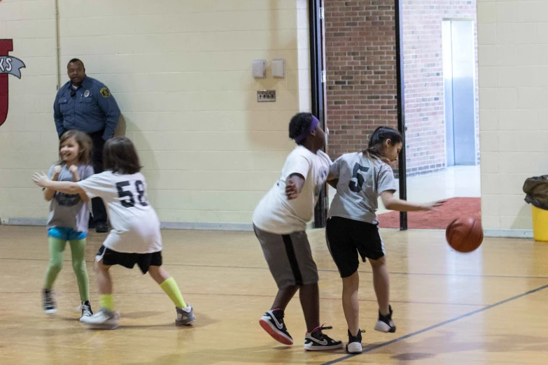 children playing a game of basketball in a gym