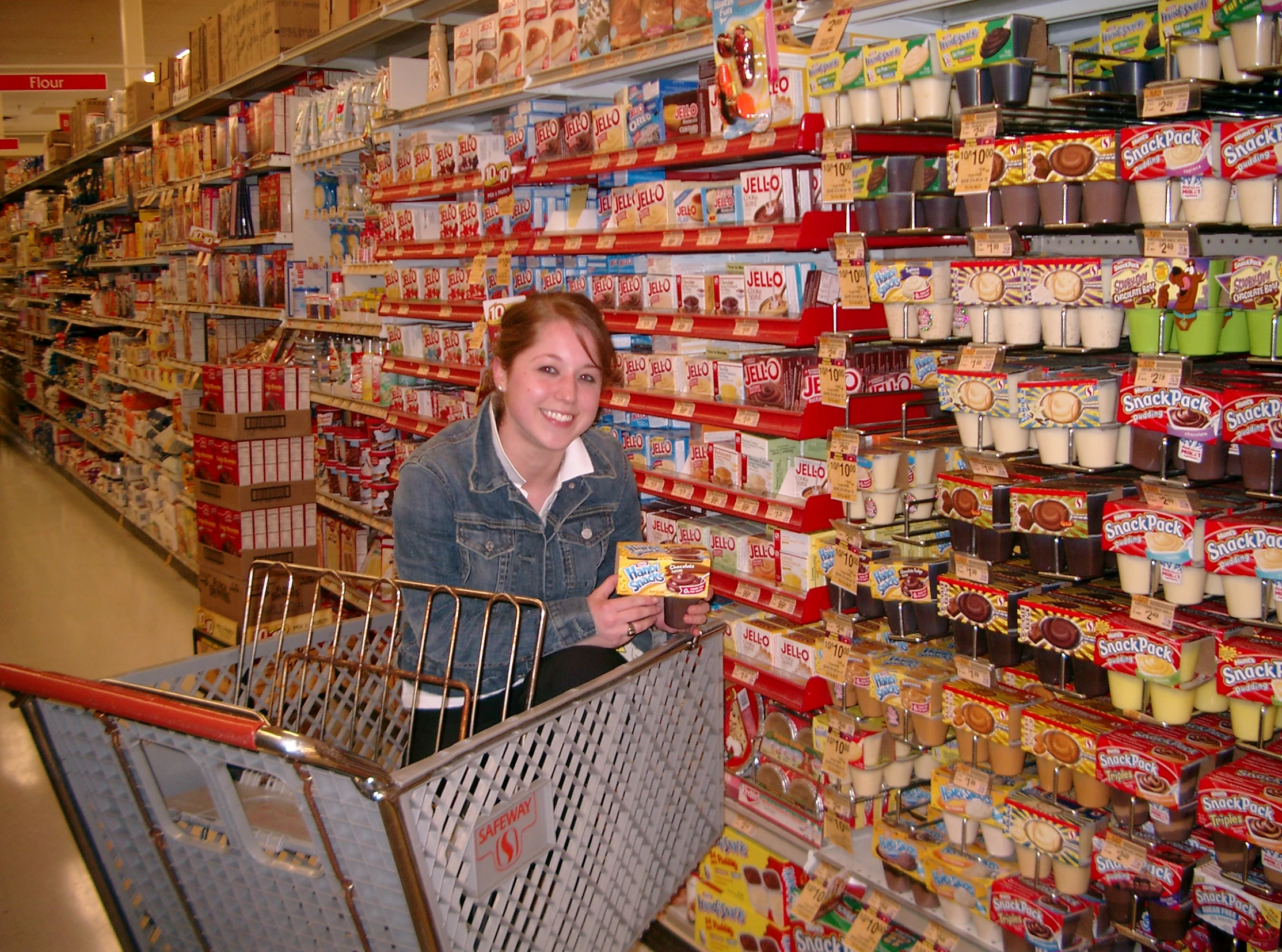 this is a grocery aisle with a woman in a shopping cart