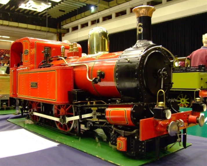 an antique style red steam engine sitting on display at a museum