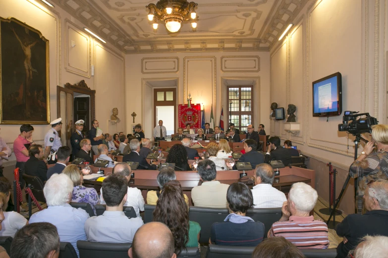 an audience of people watching on television in the middle of a large room