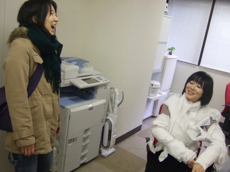 two women standing and laughing in an office