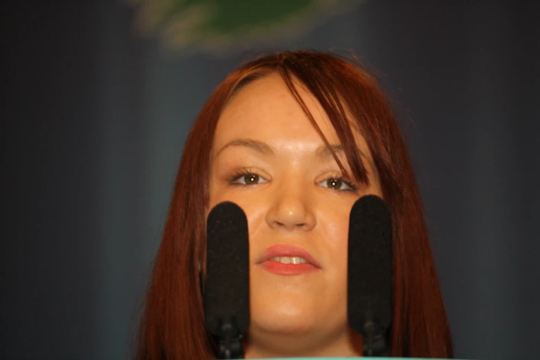 a beautiful red haired woman looking through black speakers