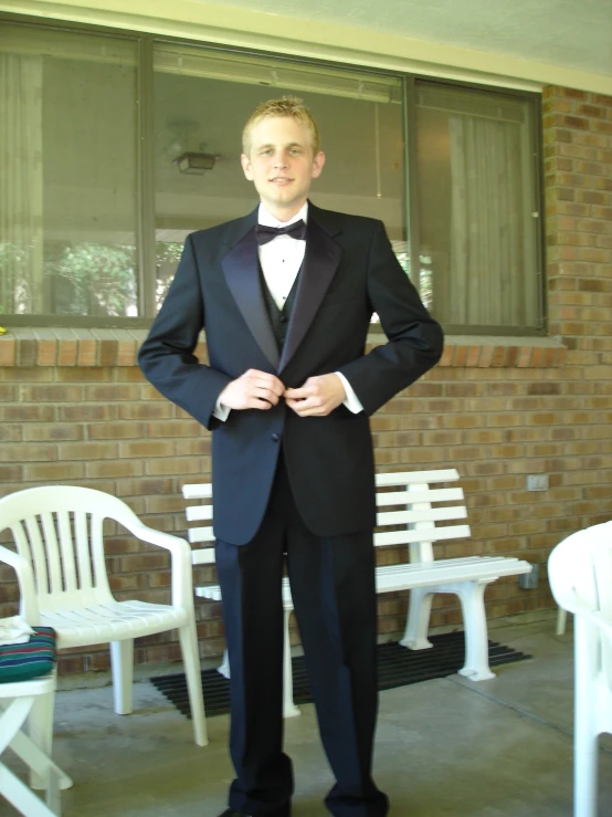 young man in tuxedo and bow tie posing for pograph