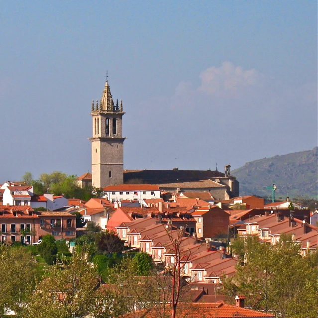 a clock tower with orange roof tops on top of a village