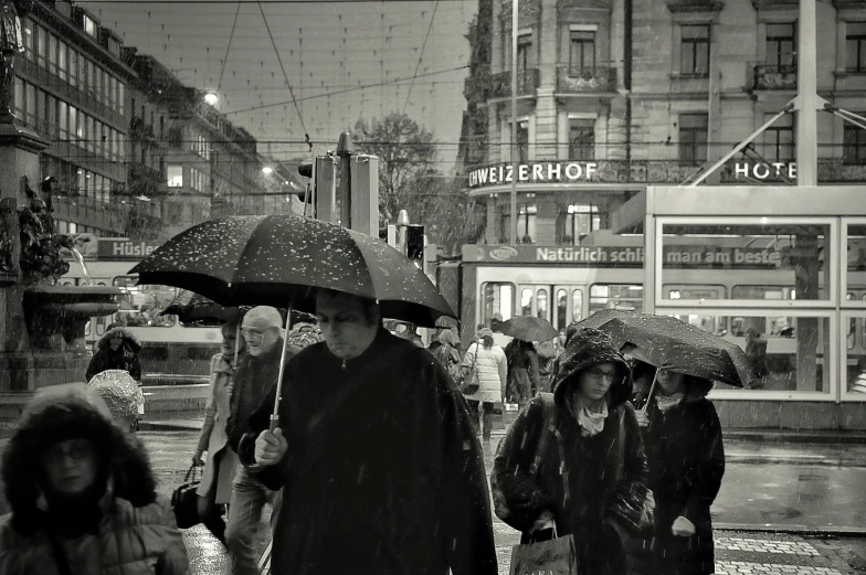 a group of people walk down a rainy street in the rain