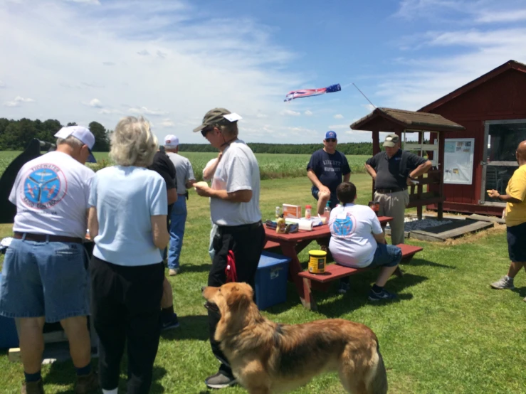 group of people and a dog eating at picnic table