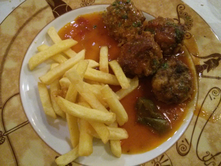 a plate of fries and meatballs with tomato sauce