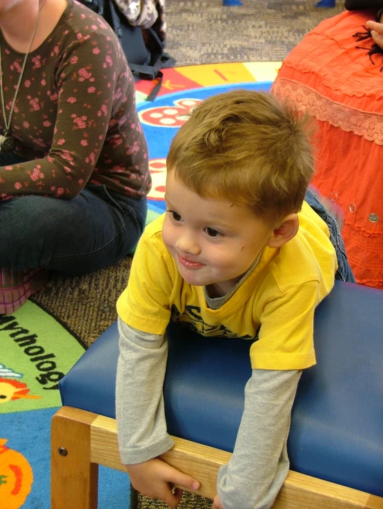 a  sitting on top of a blue chair in front of another child