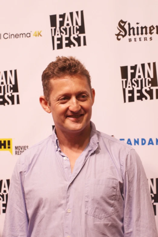 a smiling man standing next to an advert for a film festival
