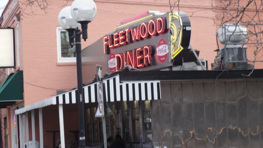 a neon sign saying hollywood diner with a bike parked on the street