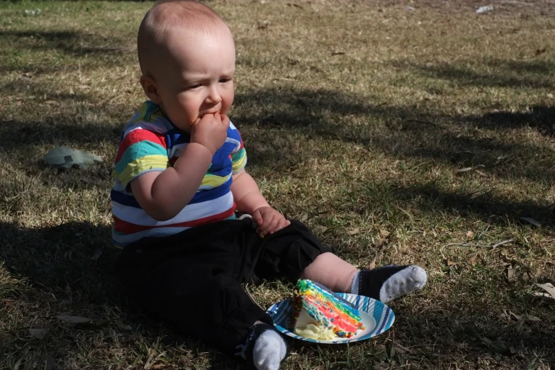 a young child with a tooth brush on sitting in the grass