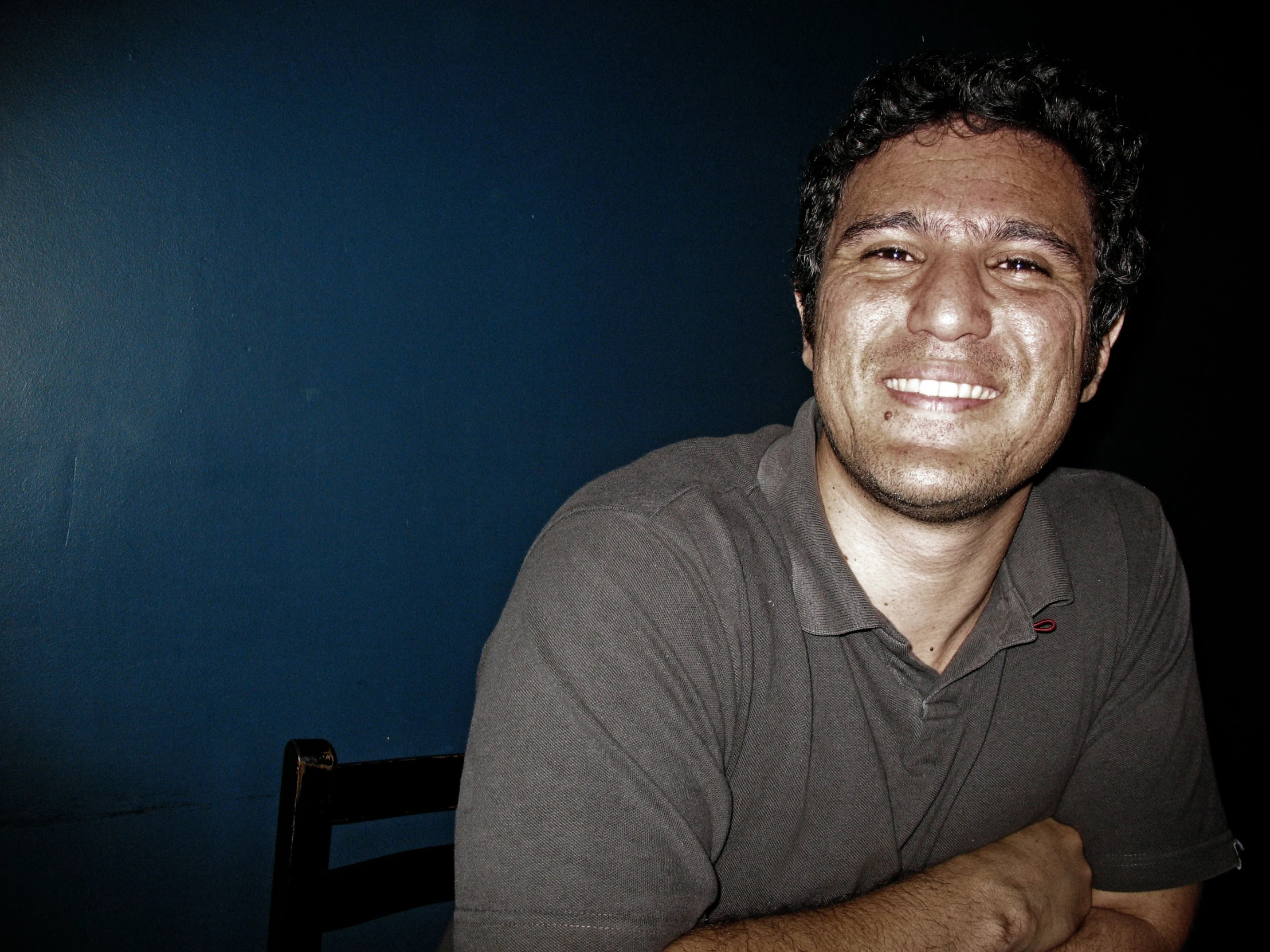 a man in a black and grey polo shirt sitting down