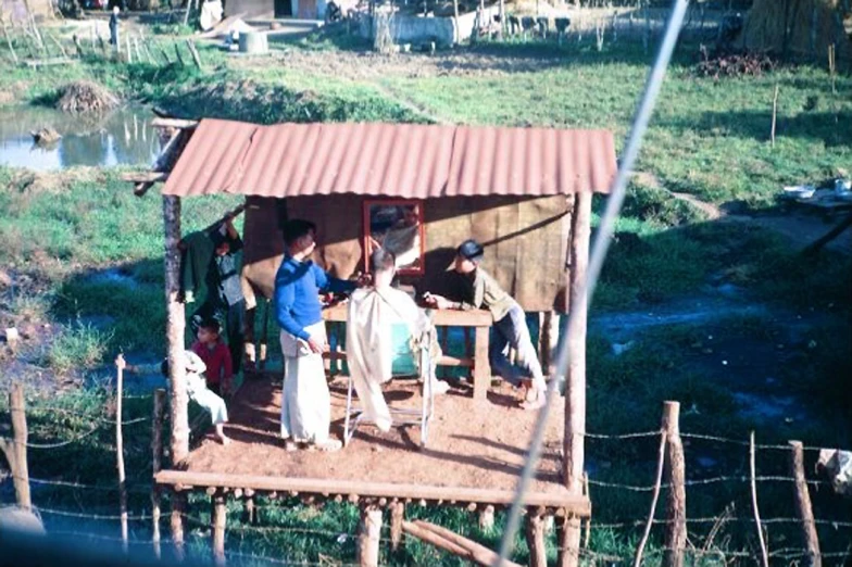 people standing in their outdoor huts that are on a farm