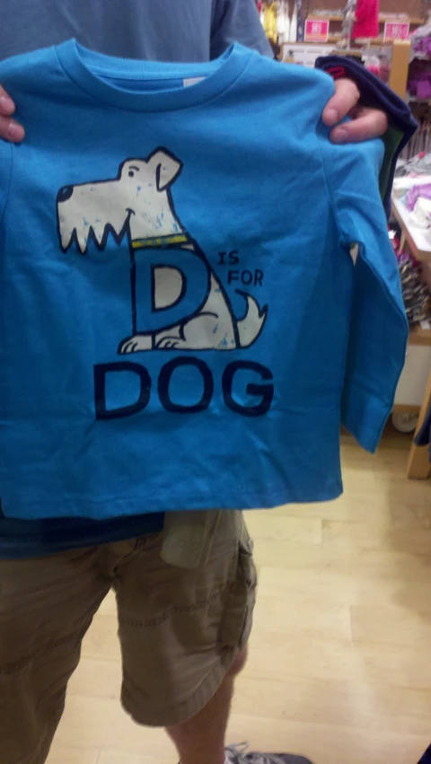 a man is holding a blue shirt with a dog on it