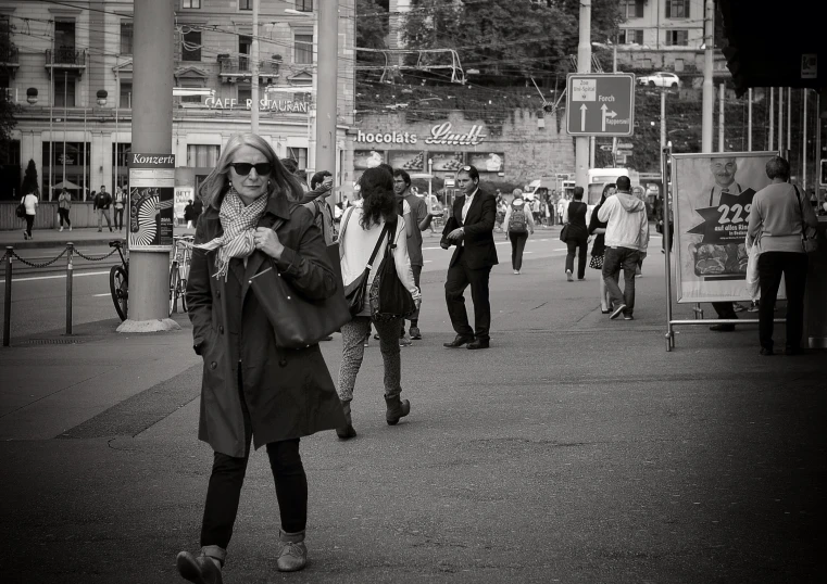 several people walk on a sidewalk outside buildings