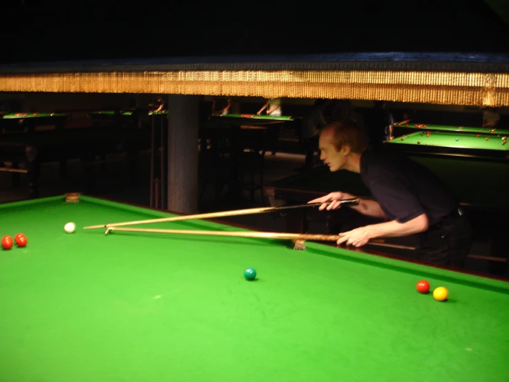 a man plays a game of pool on a green billiards table