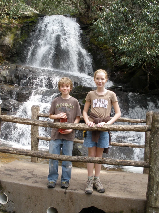 two girls posing for a po near a waterfall