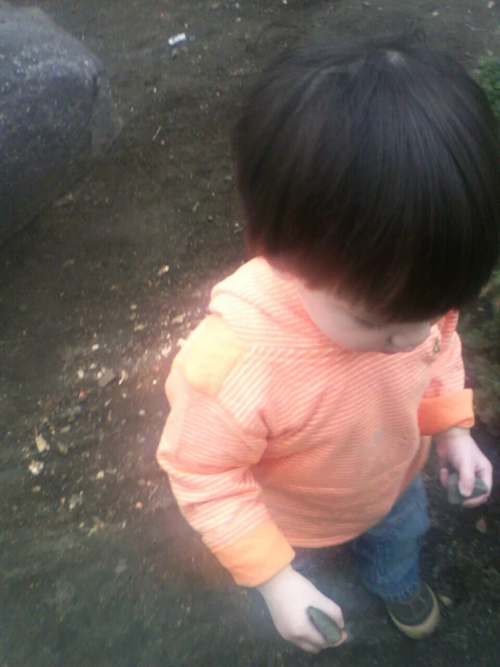 a child on the ground and holding onto a plastic container