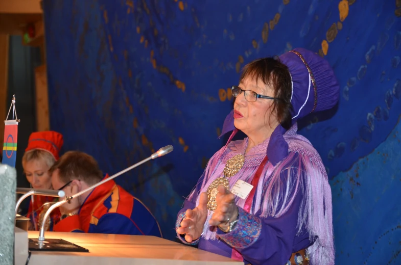 a woman standing at a podium with two children looking on