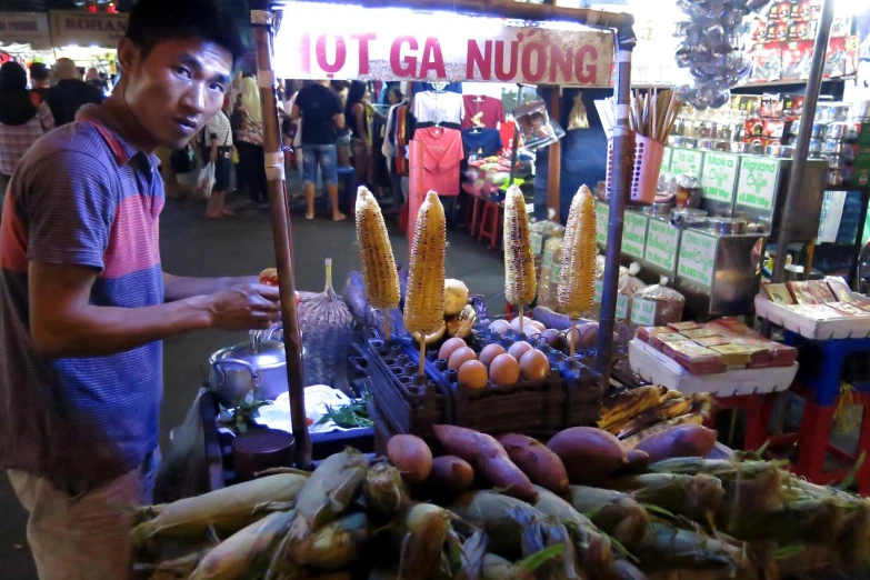 a man is selling corn and other items at a street fair