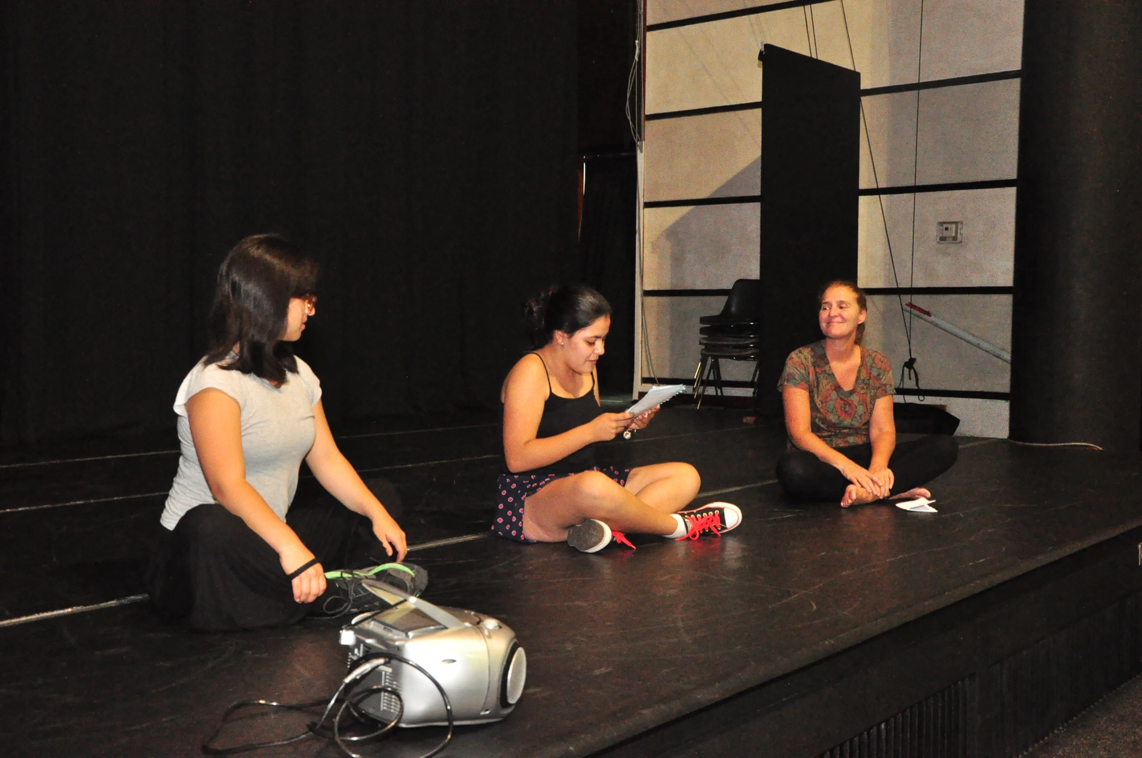 three women on stage are sitting and playing instruments