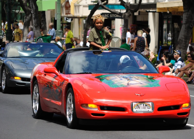 a child sitting on the top of an orange sports car