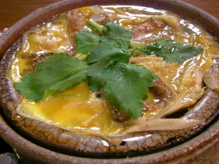 a wooden bowl filled with a soup and fresh parsley