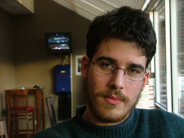 a man wearing glasses is looking to the side in an empty room