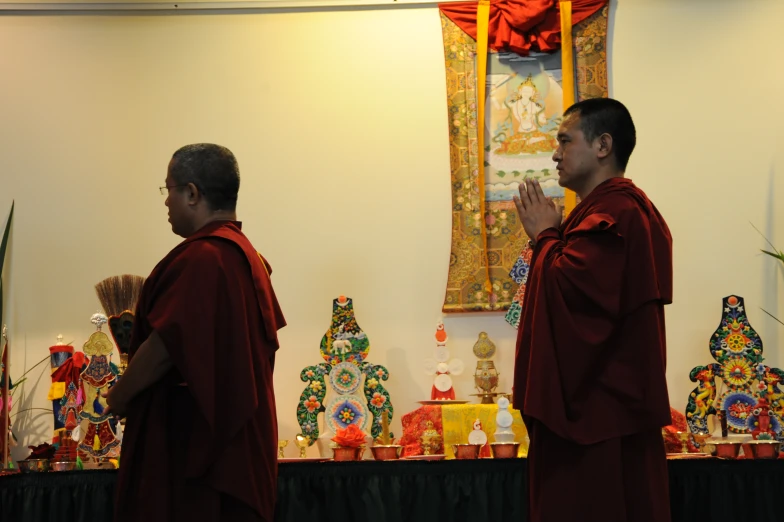 two monks looking at pictures displayed on wall