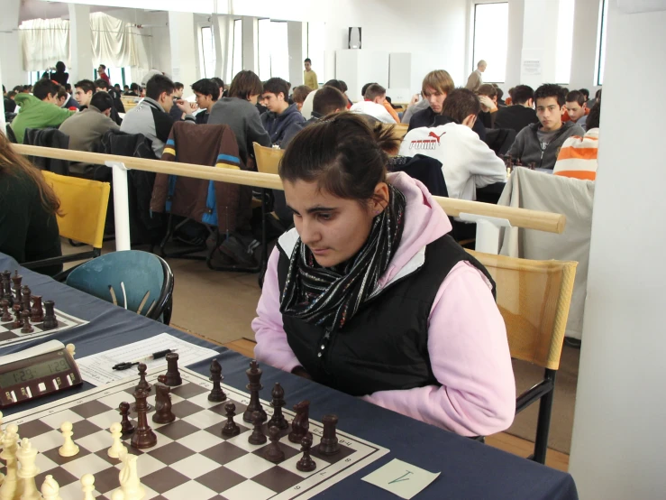 a young woman is playing chess with other people