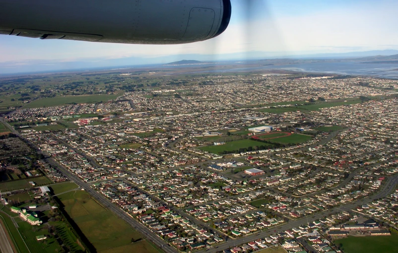 an airplane wing flying over an urban area