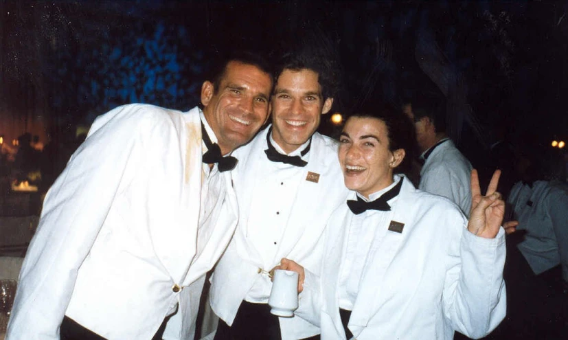 two men pose in white tuxedos for a picture