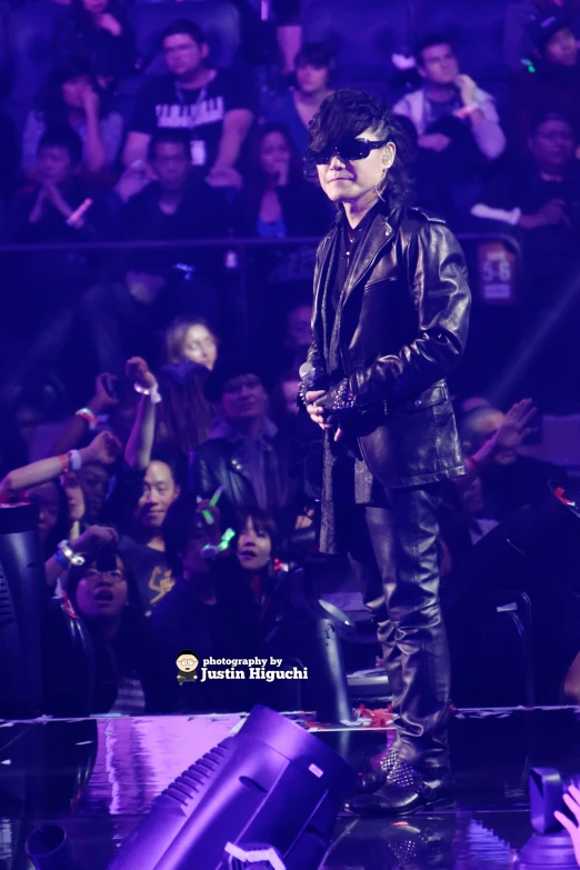 a man in leather clothes and sunglasses on stage