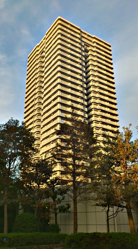 a tall building with trees around it and sky in background