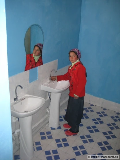 two girls are standing in the bathroom taking pictures