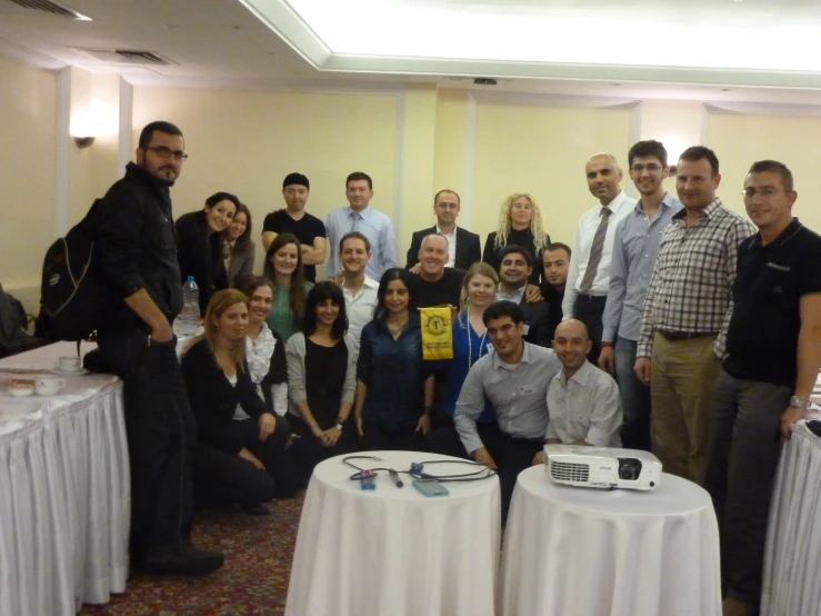 a group of people standing around a white table with a laptop