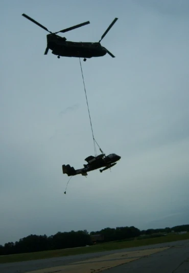 two military planes are being hoisted by a helicopter