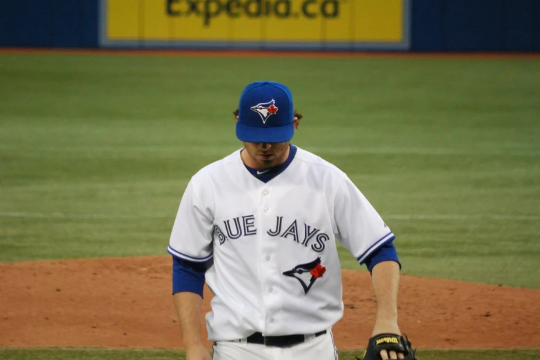 a baseball player walking on the field with his glove