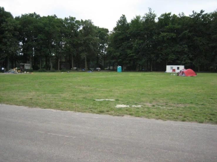 a grassy field with several toilets in the distance