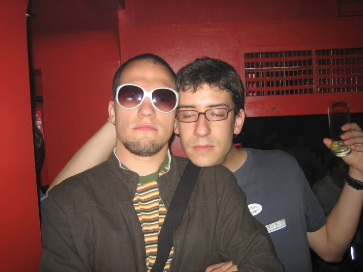 two men pose with some alcoholic beverages in their hands