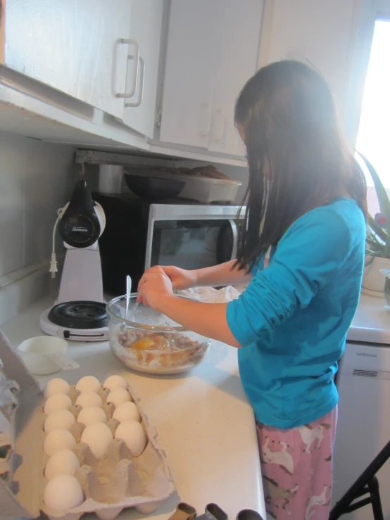 a girl in pink pants placing eggs on a table