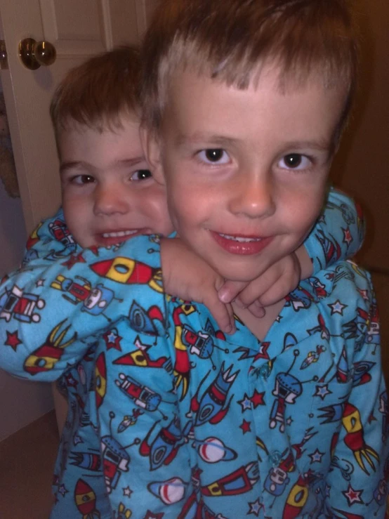 two children wearing pajamas hugging each other