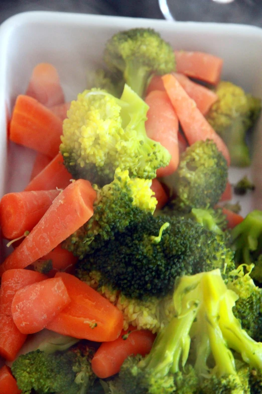 some broccoli carrots and onions are mixed in in a bowl