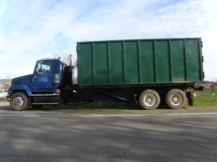 a blue and green semi - trailer truck is parked on the side of the road