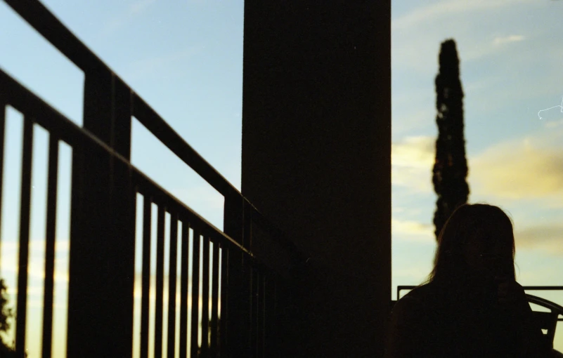 a person sitting next to a fence on a cellphone