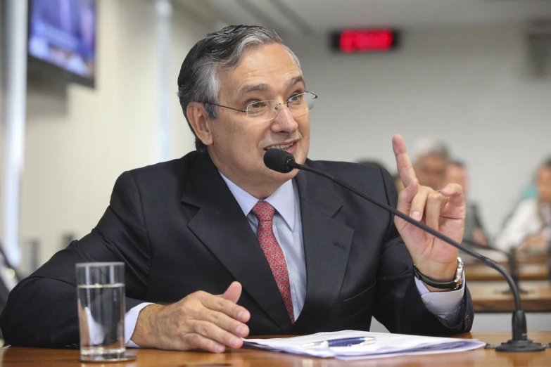 a man is speaking in front of microphones at a conference table