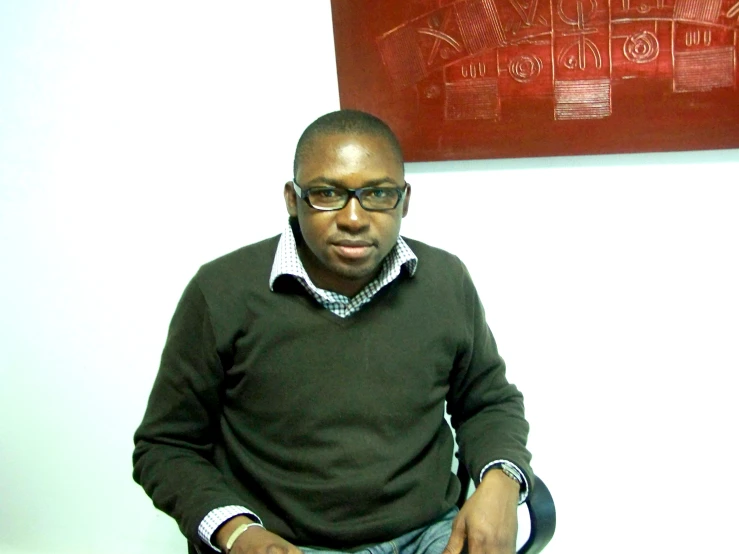 a black man is seated in front of a painting