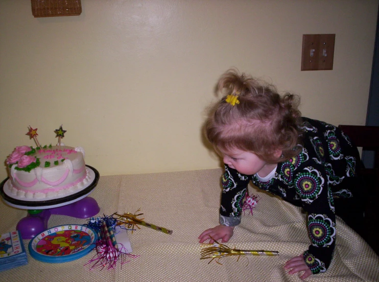 a  reaches for a pink cake on a table