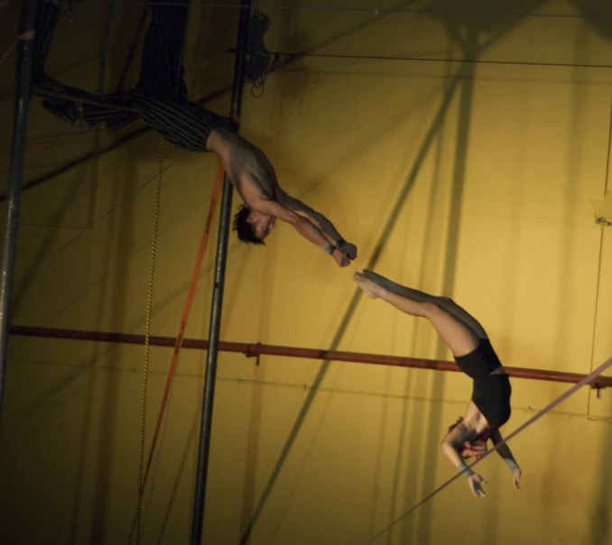 two men are performing acrobatic tricks on parallel bars